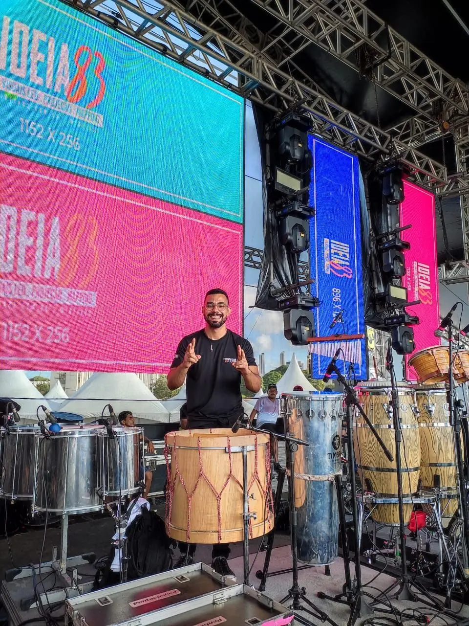 Murilo Pontes no palco de um festival, diante do set completo de percussão.