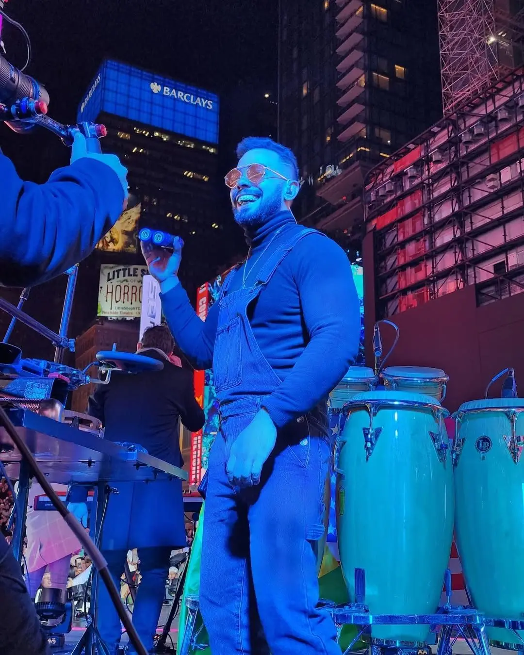 Murilo Pontes tocando com congas azuis na Times Square, à noite.