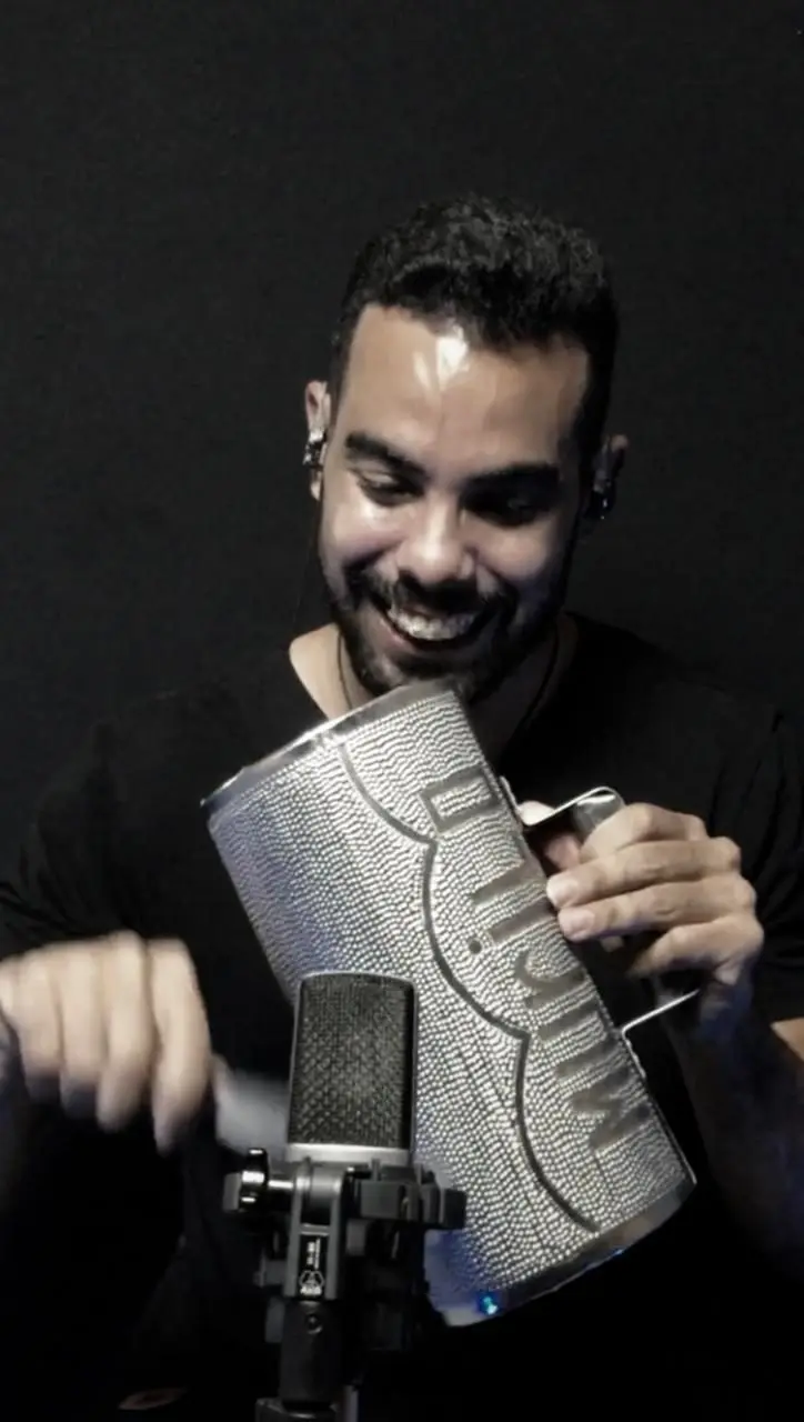 Murilo Pontes em close, com a güira de metal personalizada diante do microfone.
